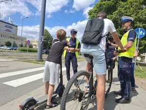 Policjanci rozmawiają z rowerzystą i użytkownikiem hulajnogi na ścieżce rowerowej