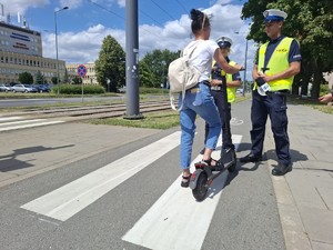 Kobieta na hulajnodze rozmawia z policjantami