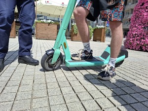 Hulajnoga na kostce brukowej trzymana przez użytkownika