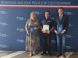 Komendant z dyrektorami szkół pozuje do zdjęcia przy ściance z napisem Policja