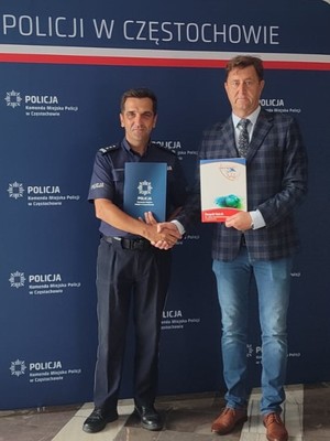 Komendant w mundurze podaje prawą rękę mężczyźnie i wspólnie pozują do zdjęcia