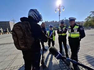 Mężczyzna w kasku na hulajnodze rozmawia z policjantami