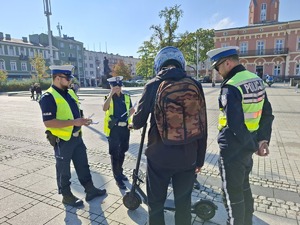 Policjanci rozmawiają z mężczyzna który stoi przy hulajnodze
