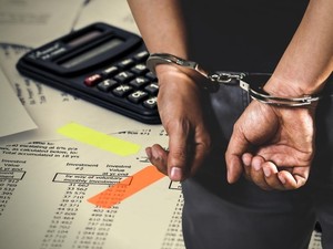 Ręce w kajdankach na tle dokumentów leżących na biurku