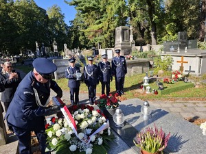 Policjanci składają wiązankę kwiatów na grobie