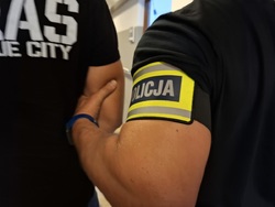Policjant trzyma pod ramię zatrzymanego mężczyznę