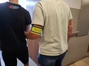 Policjant doprowadza do pomieszczenia służbowego zatrzymanego