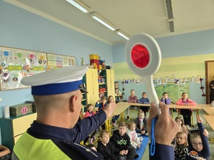 Policjant prezentuje uczniom tarczę do zatrzymywania pojazdów