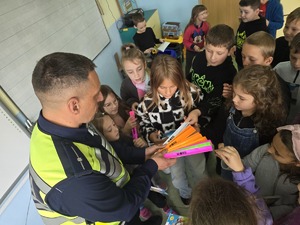 Policjant wręcza dzieciom elementy odblaskowe