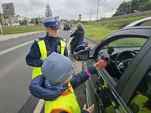 Dziecko w obecności policjantki wręcza jabłko kierującemu