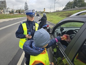 Dziecko w obecności policjantki wręcza jabłko kierującemu