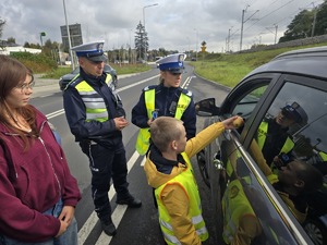 Dziecko w obecności policjantów wręcza jabłko kierującemu