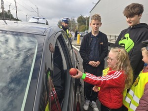 Dzieci stoją obok pojazdu, jedno z nich podaje jabłko kierującemu