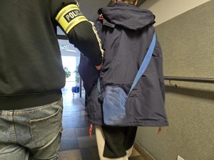 Policjant doprowadza zatrzymanego