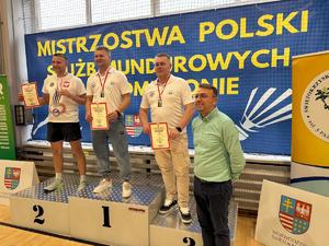 Trzech zawodników stoi na pudłach podium