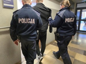 Policyjny patrol doprowadza zatrzymanego do pokoju służbowego