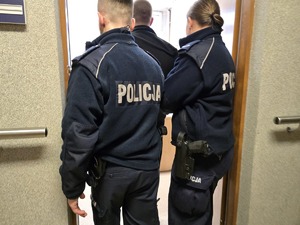 Policyjny patrol wchodzi do pomieszczenia z zatrzymanym