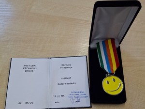 Odznaka z książeczką leżą na stoliku obok siebie