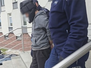 Policjanci doprowadzają zatrzymanego schodami