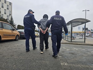 Policjanci doprowadzają zatrzymanego