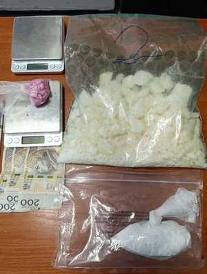 Zabezpieczone narkotyki, waga i gotówka ułożoner na stoliku