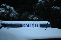 Napis Policja na tle ośnieżonego lasu