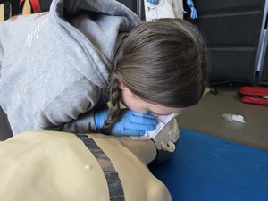 Zawodniczka wykonuje wdechy ratunkowe na fantomie