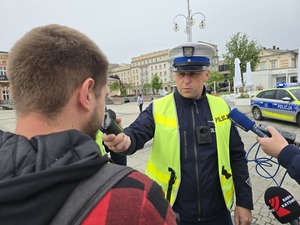 Policjant trzyma urządzenie w które dmuch mężczyzna