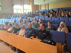 Policjanci wśród widzów siedzą w auli komendy