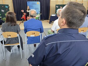 Policjant siedzi w sali gimnastycznej podczas akademii szkolnej