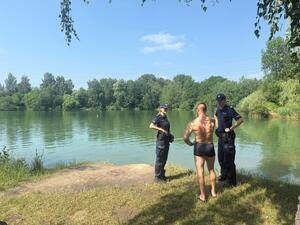 Policjanci rozmawiają z mężczyzną przy zbiorniku wodnym