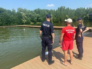 Policjanci rozmawiają przy zbiorniku wodnym z ratownikiem