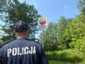 Policjant kontroluje znaki dotyczące zakazu kąpieli