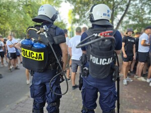 Policjanci stoją przy zabezpieczeniu wejścia na stadion sportowy