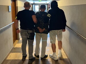Policjanci doprowadzają zatrzymanego korytarzem