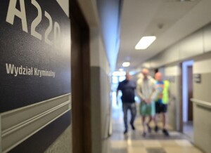 Policjanci doprowadzają zatrzymanego korytarzem