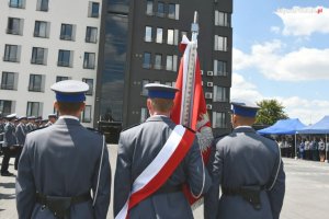 Poczet sztandarowy na tle budynku Komendy Miejskiej Policji w Dąbrowie Górniczej.