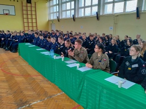 Umundurowani policjanci i uczniowie klas mundurowych podczas debaty. debata odbywa się w sali gimnastycznej szkoły średniej.