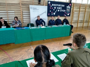 Umundurowani policjanci i uczniowie klas mundurowych podczas debaty. debata odbywa się w sali gimnastycznej szkoły średniej.