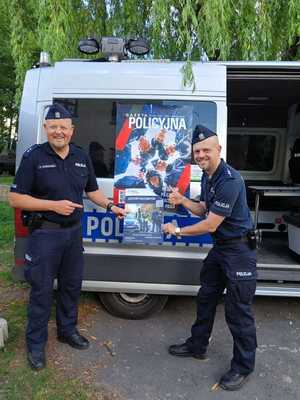Na zdjęciu widać umundurowanych policjantów z plakatem promującym służbę w policji