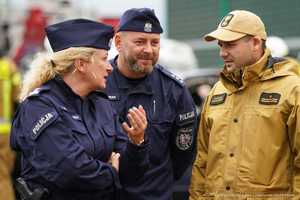 Na zdjęciu widzimy umundurowanych strażaków i policjantów oraz oznakowane radiowozy tych służb podczas działań na drodze ekspresowej.