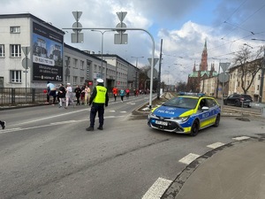 Umundurowani policjanci i radiowozy oznakowane, zabezpieczający bieg walentynkowy.