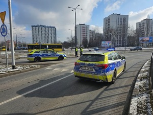 Umundurowani policjanci i radiowozy oznakowane, zabezpieczający bieg walentynkowy.