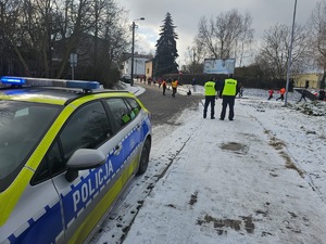 Umundurowani policjanci i radiowozy oznakowane, zabezpieczający bieg walentynkowy.