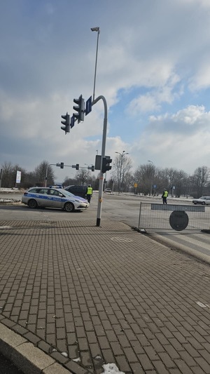 Umundurowani policjanci i radiowozy oznakowane, zabezpieczający bieg walentynkowy.