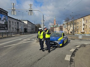 Umundurowani policjanci i radiowozy oznakowane, zabezpieczający bieg walentynkowy.