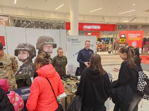 Umundurowani policjanci i wojskowi podczas promocji służb mundurowych w centrum handlowym.