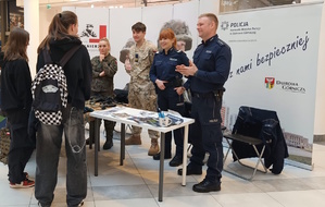 Umundurowani policjanci i wojskowi podczas promocji służb mundurowych w centrum handlowym.