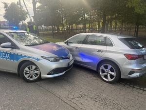 Oznakowane radiowozy i umundurowani policjanci w trakcie zatrzymywania pojazdu