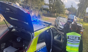 Oznakowane radiowozy i umundurowani policjanci w trakcie zatrzymywania pojazdu